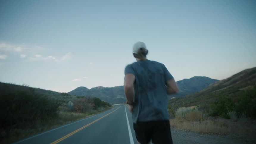 A man runs along a remote mountain highway on an autumn day