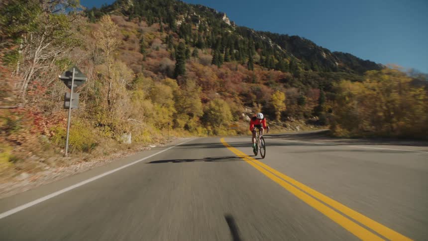 A car rides by a cyclist on the road