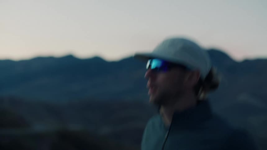 Man runs through the mountainous countryside near sunset