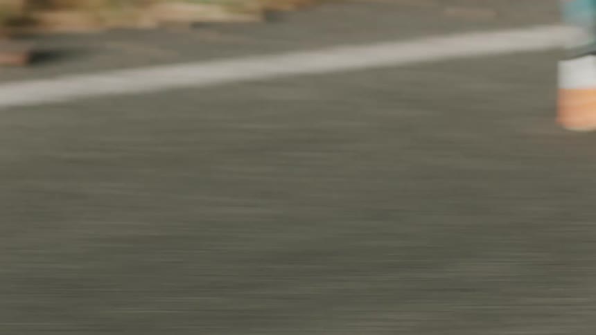 A man is running on a street next to a rural grassy area