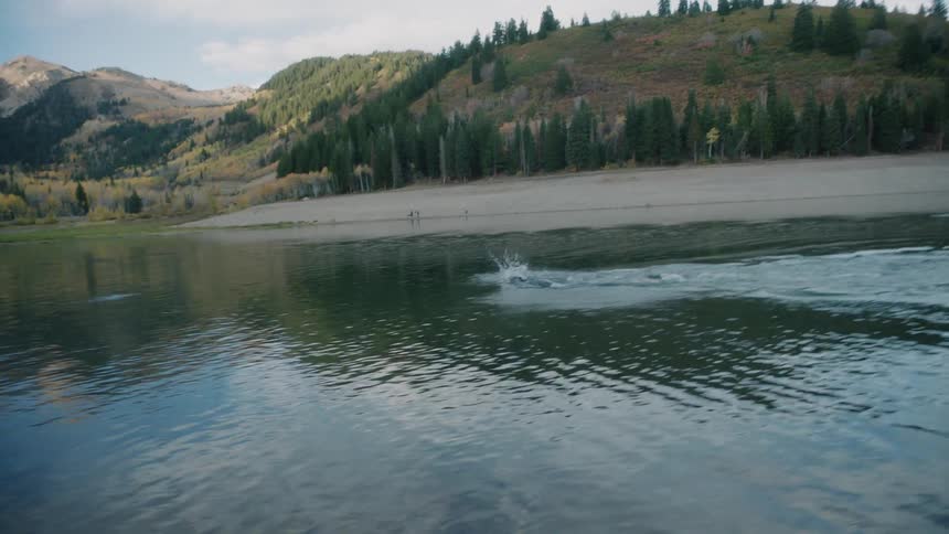 Person swimming in a lake surrounded by mountains