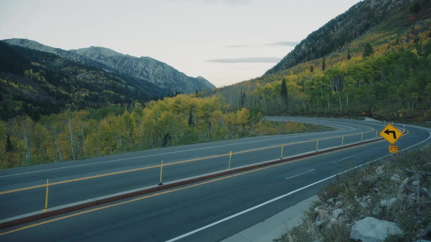 A vehicle disappears as it comes around a bend in the mountains