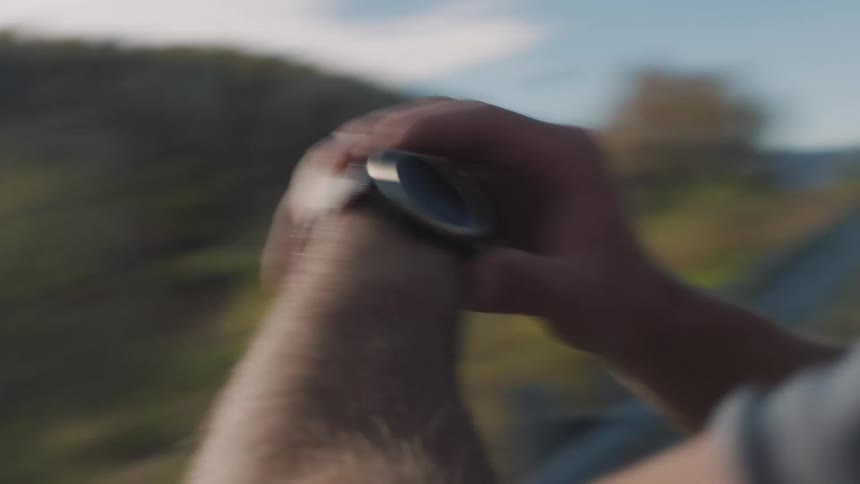 Man on a mountain trail setting his wristwatch