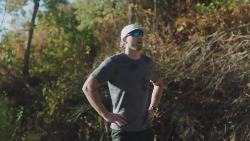 A man jogging on a road stops to catch his breath