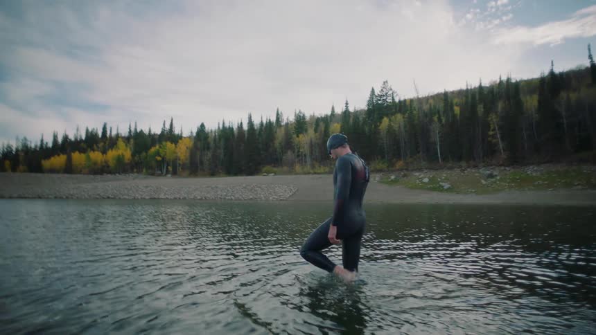 A man is wading through the water of the lake
