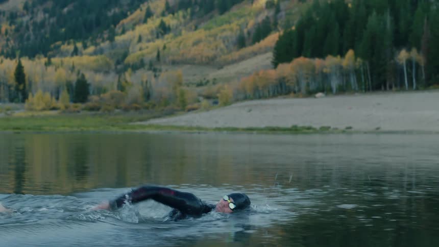Man in swimming cap starting to swim in a calm lake