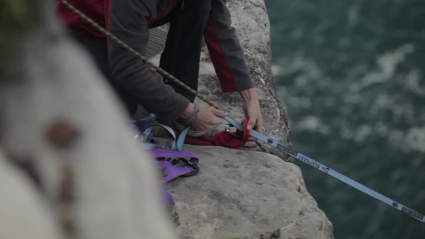 A man sets or belays a line across body of water