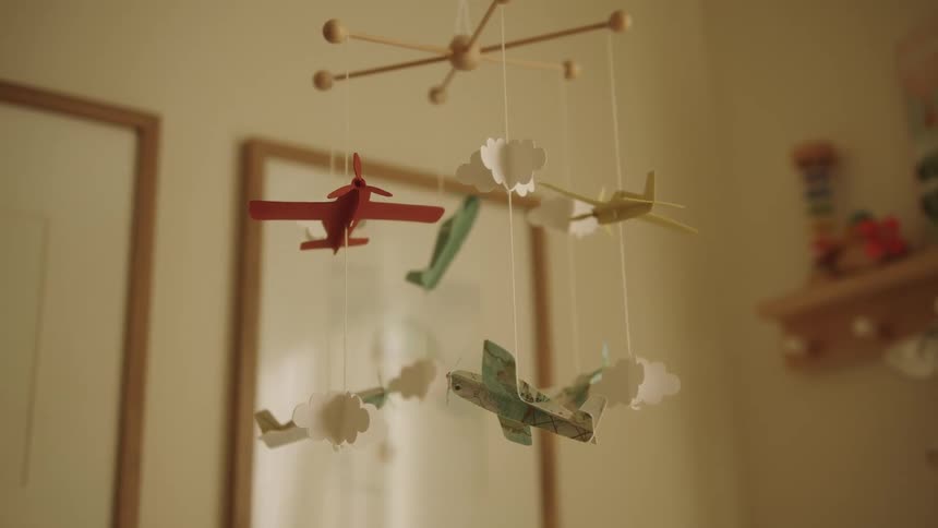 Mobile containing planes and clouds floats in a baby room