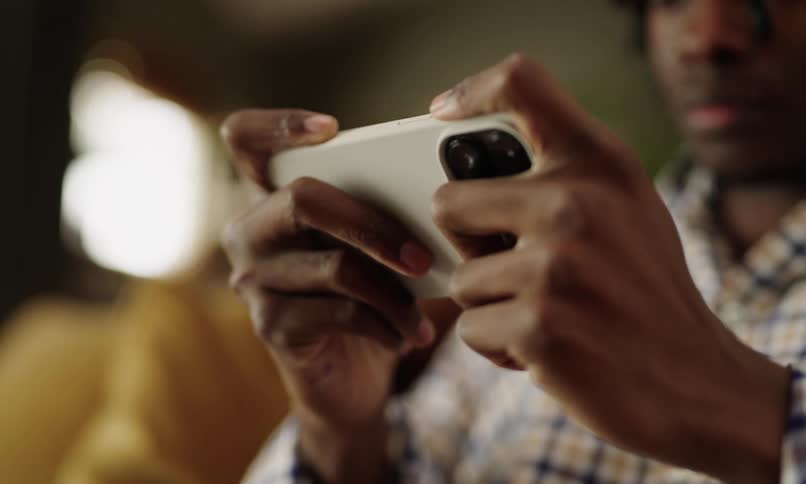 Male youth plays a game on his smartphone while sitting on a sofa