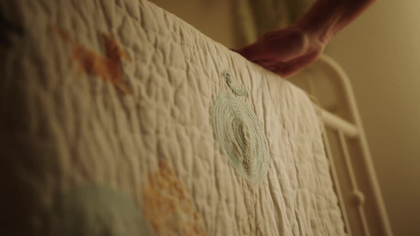 Hand adjusting a thin blanket on the side of a crib