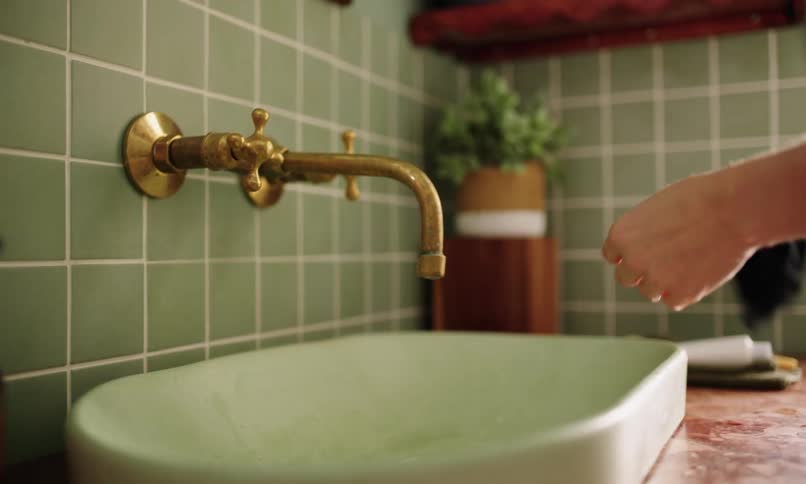 Pair of hands washing hands in bathroom sink and drying with black towel