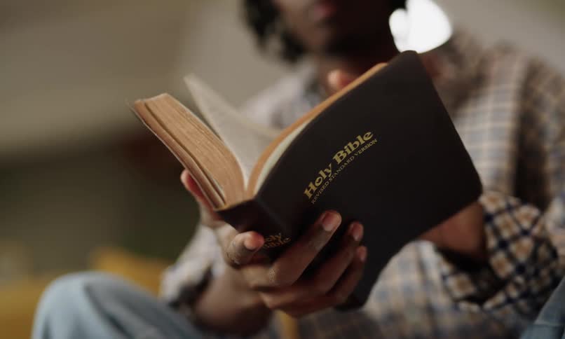 Pair of hands holding and leafing through a bible
