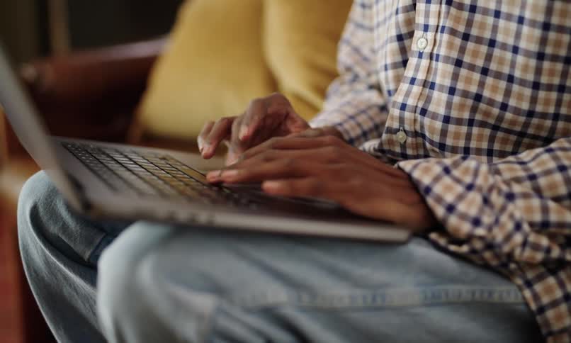 Man rests laptop on his lap and types on it