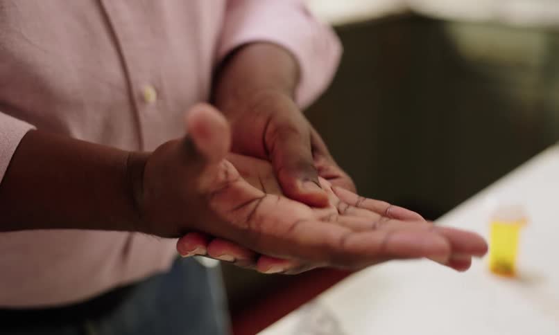 A close up of a person rubbing or massaging the palm of their hand with the thumb of the other hand