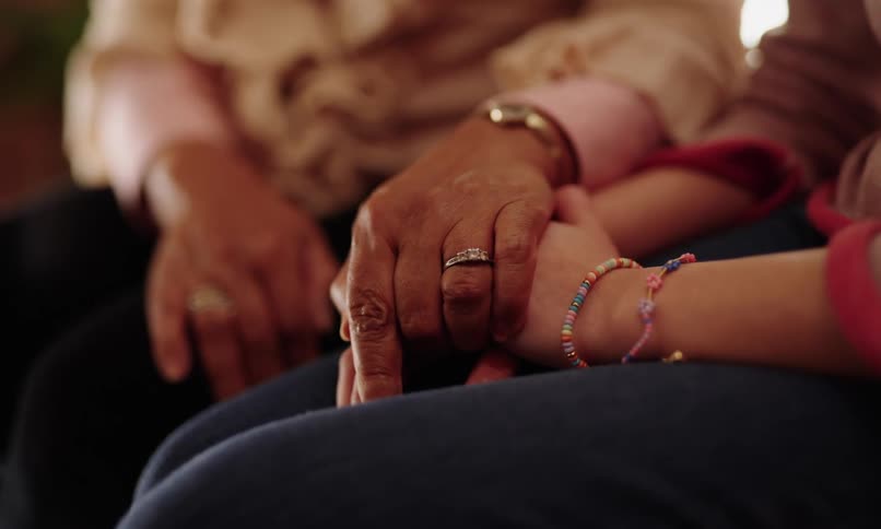 Elderly persons hand being placed on top of a childs hands