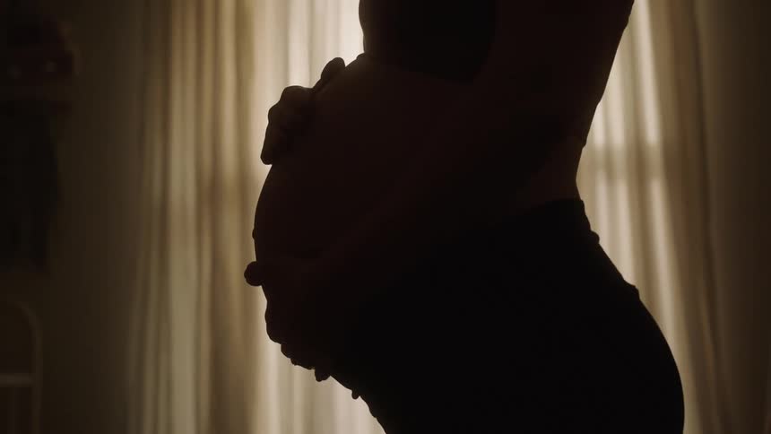 Woman placing her hands on her pregnant belly