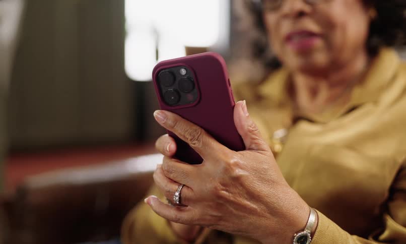 Close up of hands of an elderly woman sitting interacting with an iphone