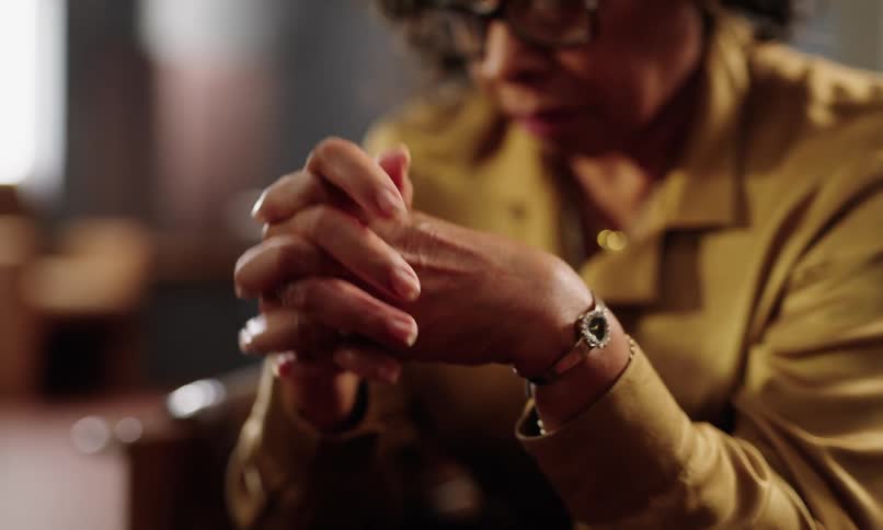 Woman sitting with fingers intertwined anxiously