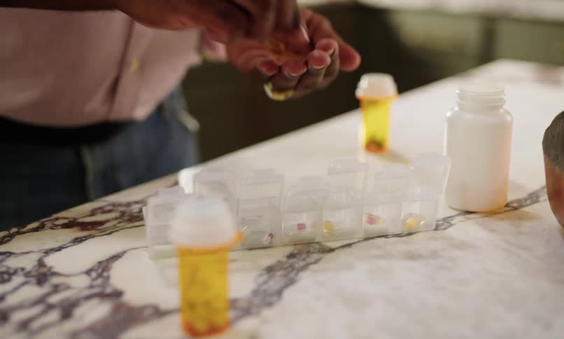 Pair of hands sorting medicines inside a jar with dividers