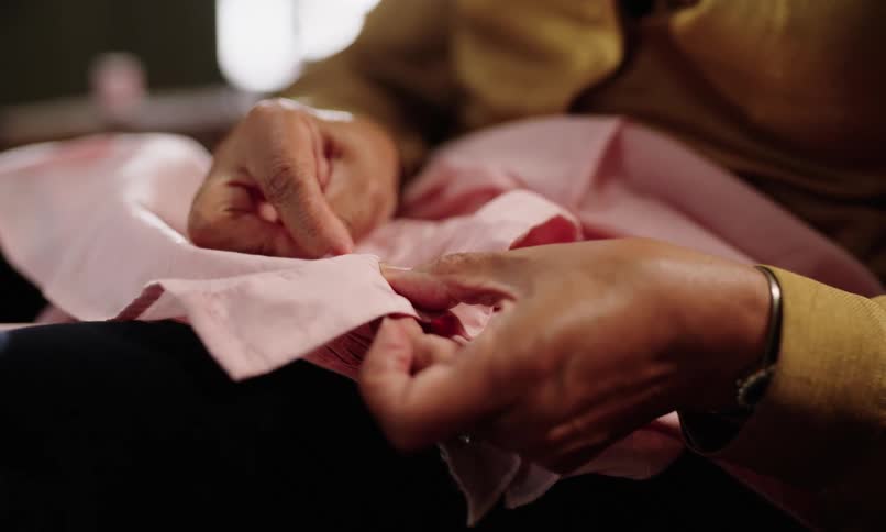 Sitting woman hand stitchs a piece of cloth