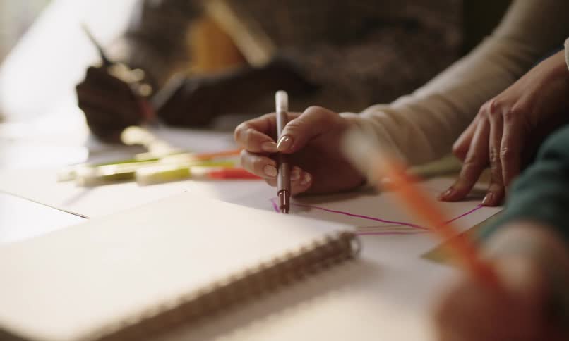 A group of people drawing with colored markers on a piece of paper