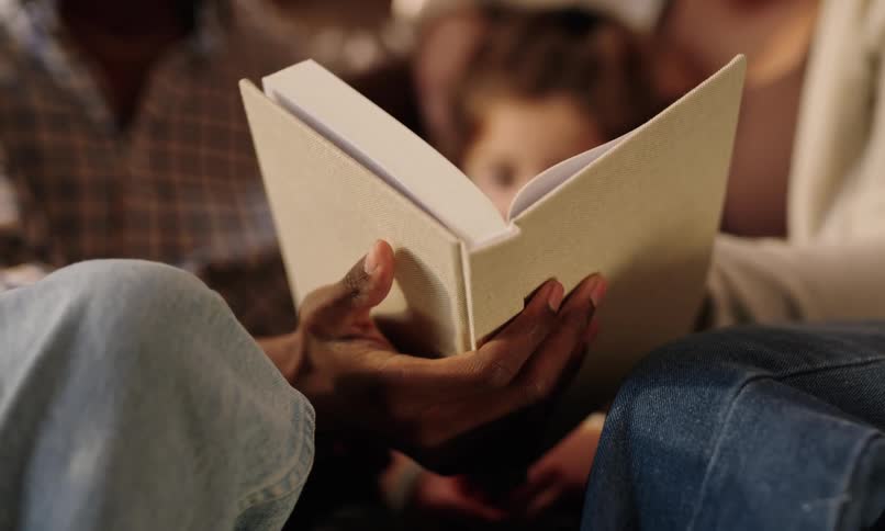 Mother father and daughter sitting next to each other reading a book