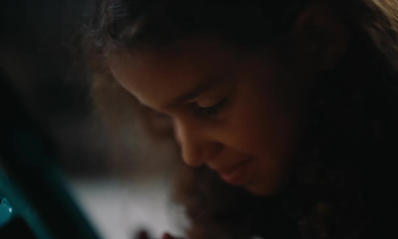 The face of a little girl looking down and then begins to give a subtle smile