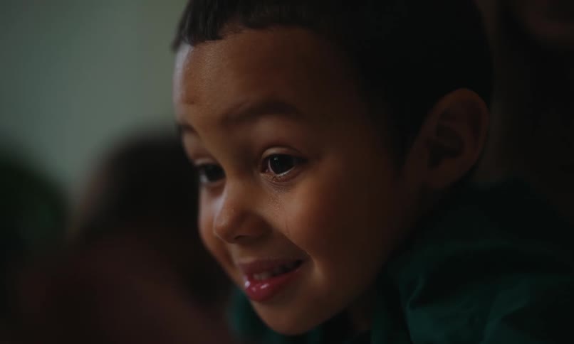 A child smiles while waving a toy car around