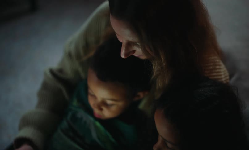Mother sitting with her two young children watching on a tablet