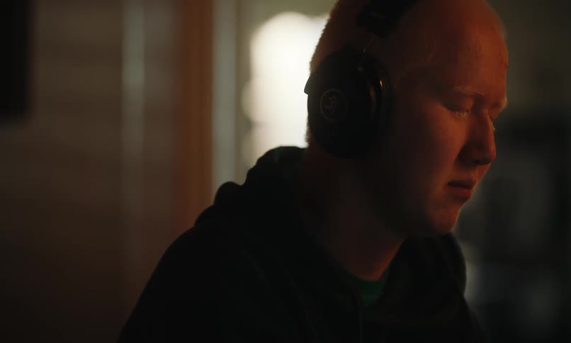 Portrait of a person putting on headphones and keeping eyes closed