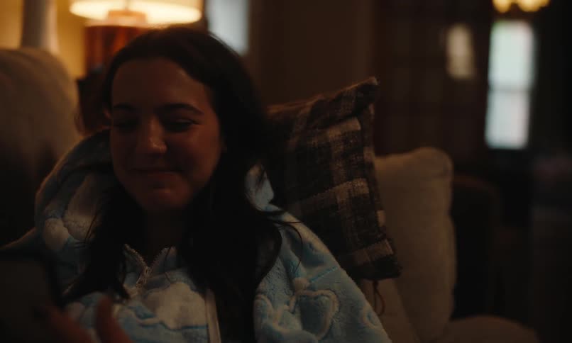 A clip of a lady smiling while laying on a couch