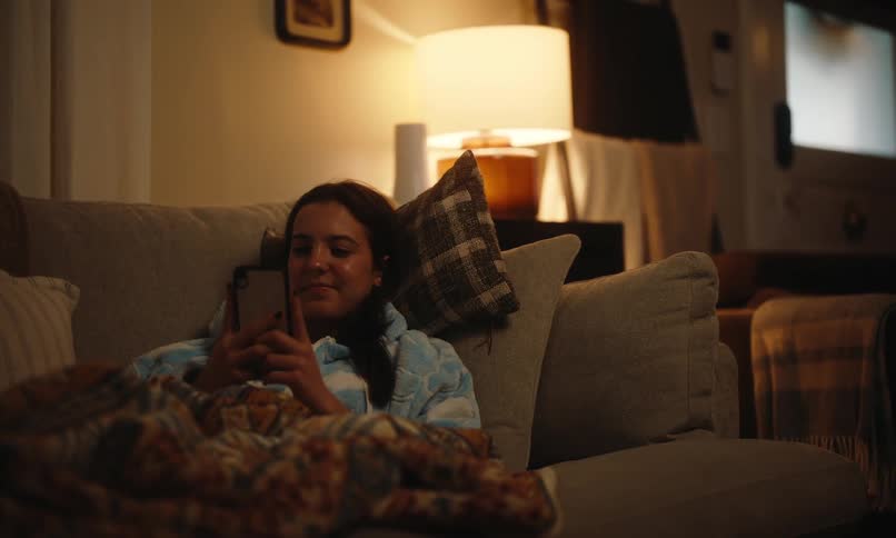 Smiling woman goes to sleep on the couch after using her smartphone