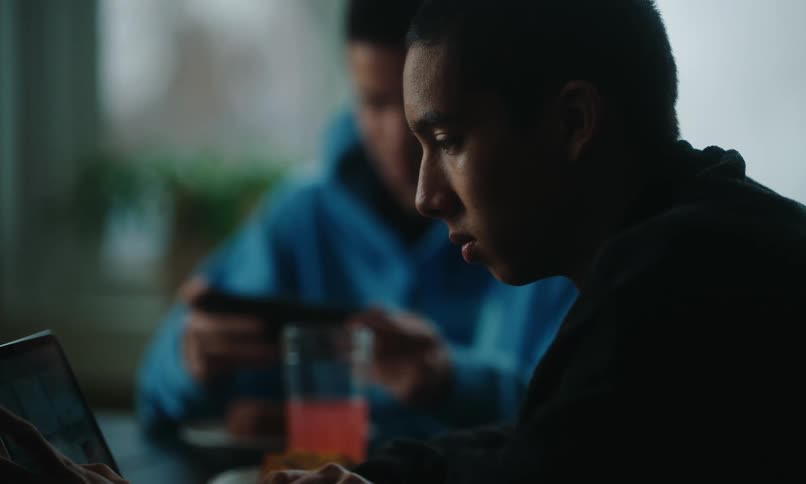 Teenagers are using their laptop and cell phone at the table