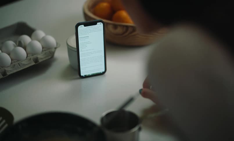 Woman cooking and looking at a recipe on a smartphone