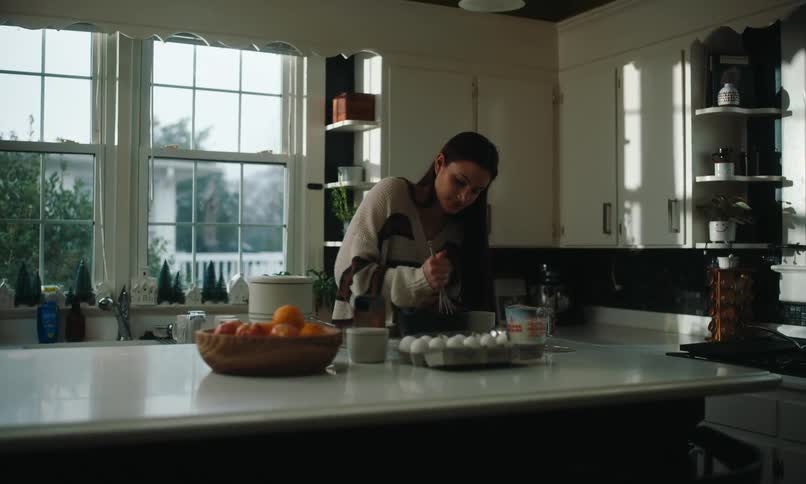 A woman is stirring with a whisk in her kitchen