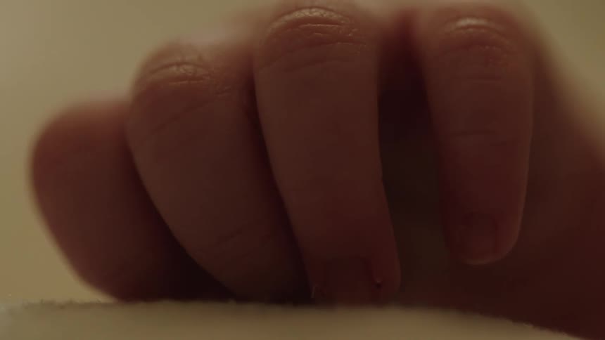 Close up of a newborn babys hand resting on a white blanket