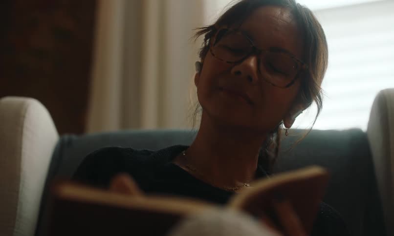 Woman sitting in a rocking recliner writes in a journal