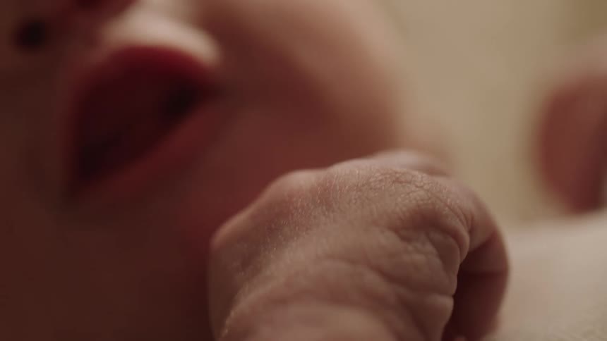 Close up of a babys mouth putting fingers in while lying down