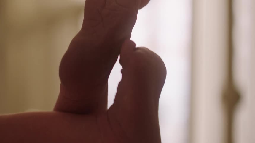 Tiny baby feet with soft lighting in the background emphasizing their delicate and tender features