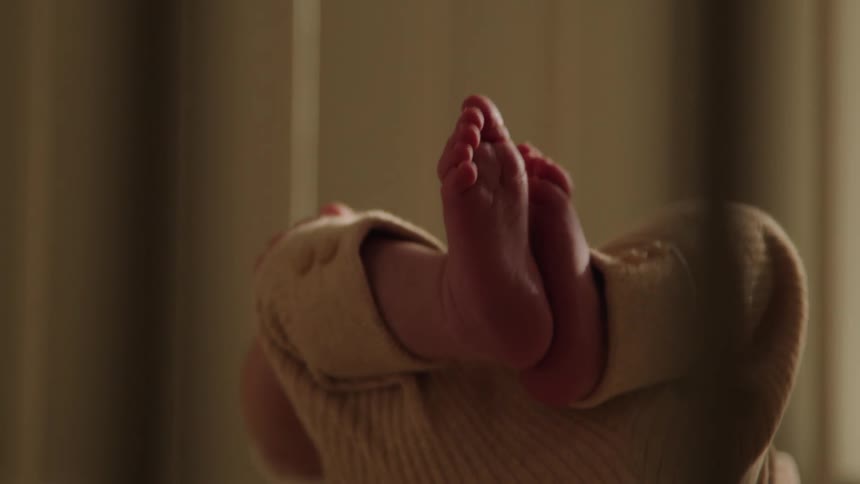A baby swings his legs and arms in the crib