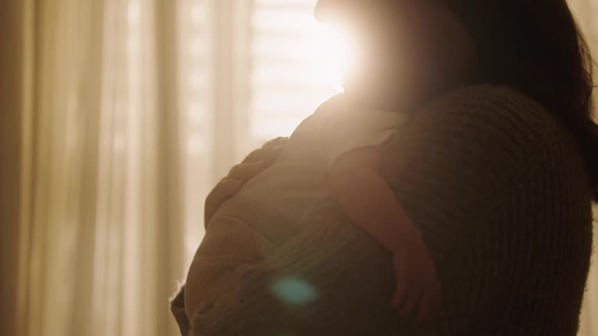A woman holding a baby on her lap and she is stroking his back