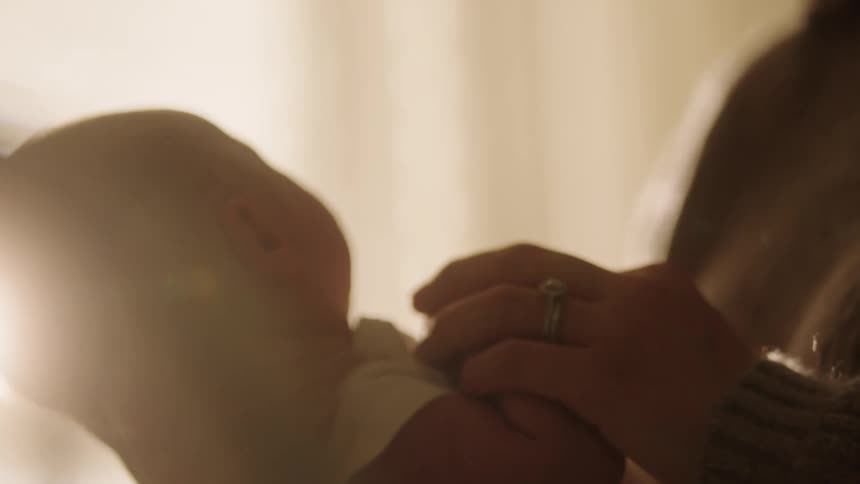 A mother gently holding a newborn baby in a warm and tender moment