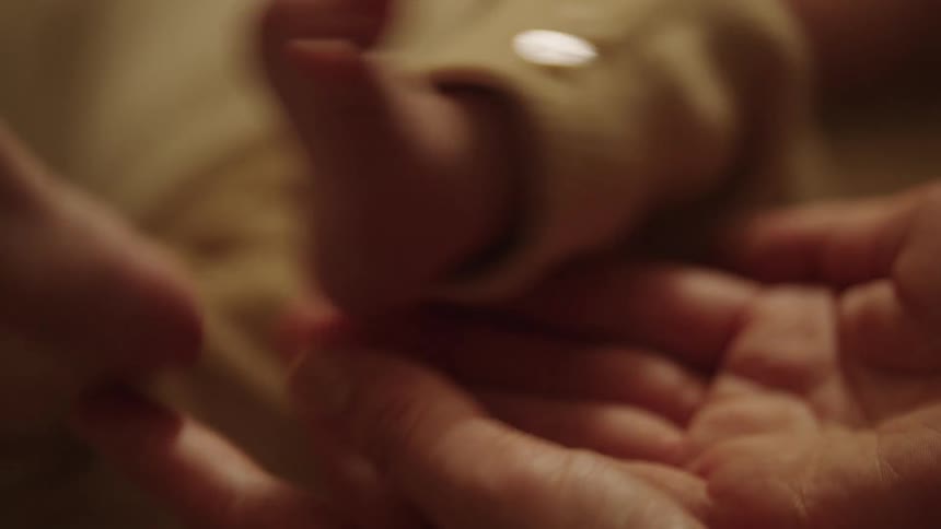 A close up of a persons hands gently holding a babys feet