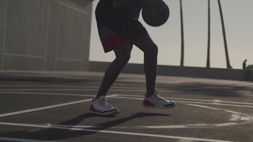 Man playing basketball outdoors on a cement court