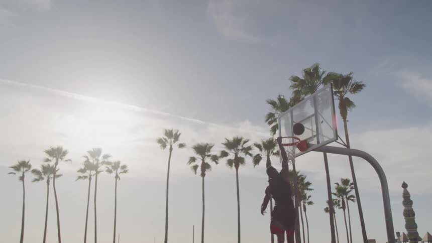 Man jumping and missing a shot on an outdoor basketball court