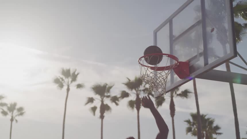 Man playing basketball on a cloudy day takes a shot but misses
