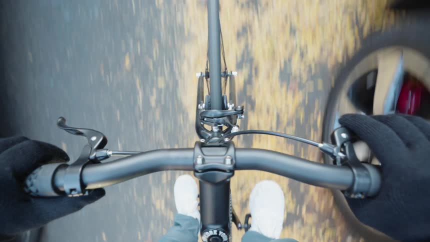 POV shot of an adult riding a bicycle on a paved road