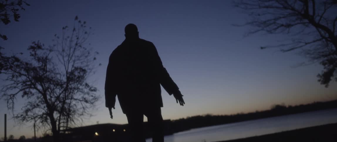 A man walks near water at dusk