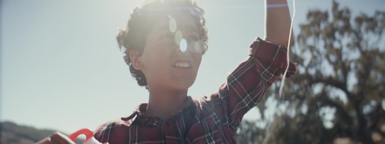 Boy with happy facial expression holding a kite string outdoors