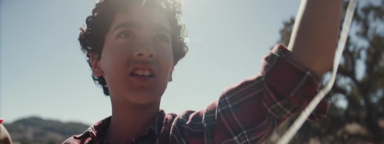 A boy is flying a kite on a sunny day